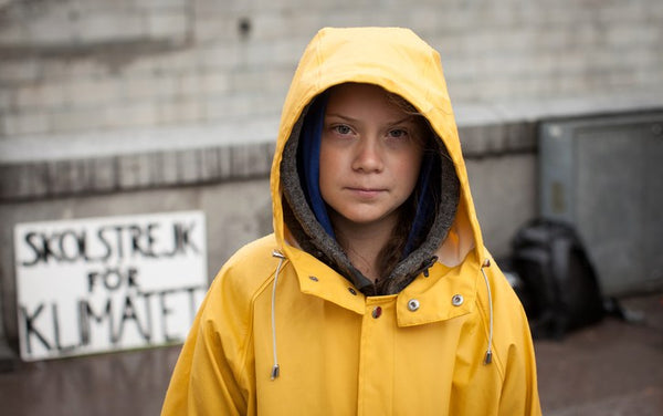 Child in yellow rain jacket looking at camera. 