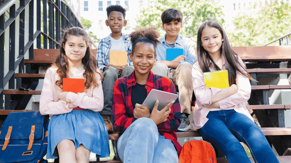 A group of students sits on the steps outside of their school. They all learn differently so differentiated learning is ideal for larger groups of students.