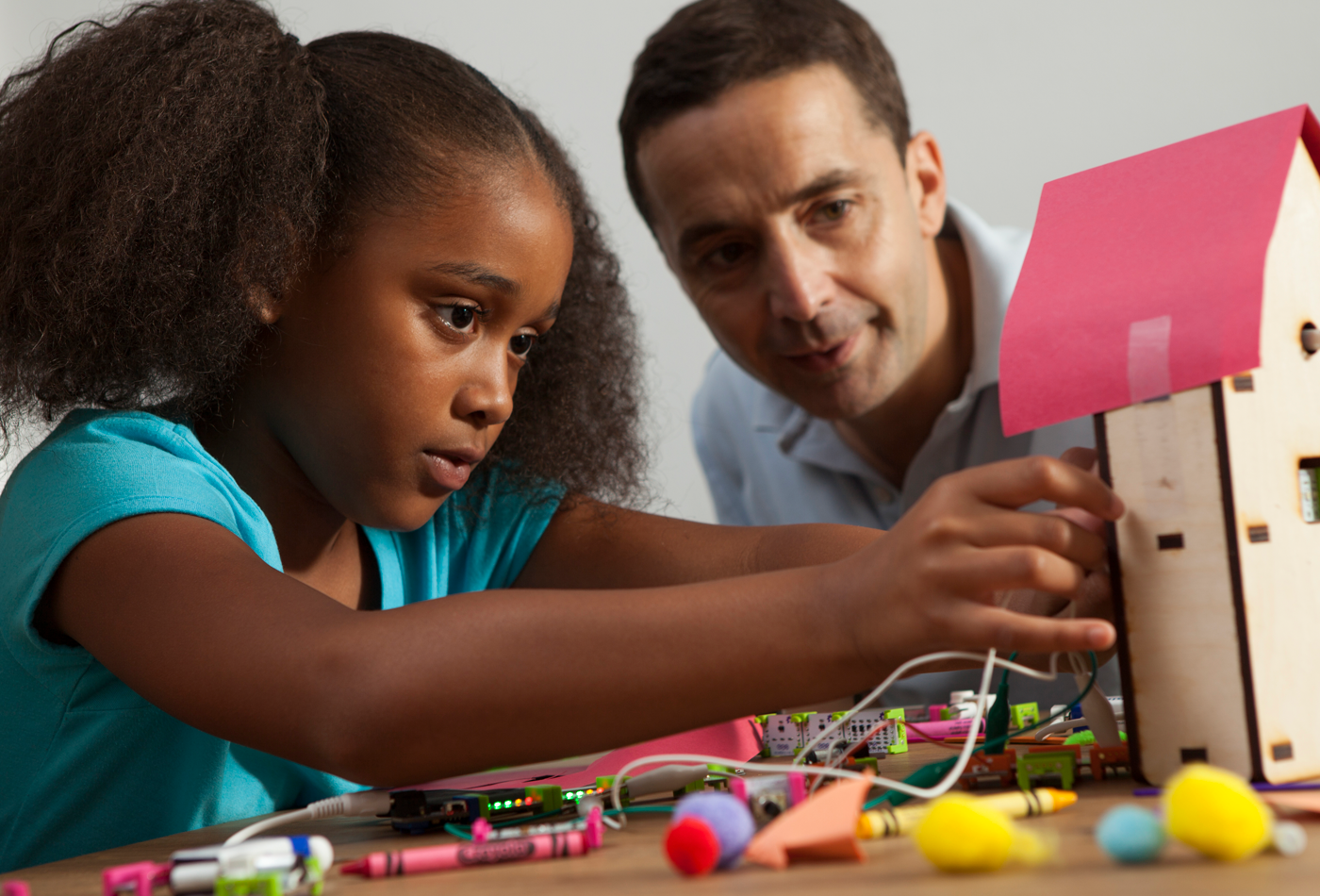 Girl building house with STEM teacher.