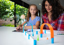 Mother and daughter driving mini STEAM robot through a maze with pins and cones.