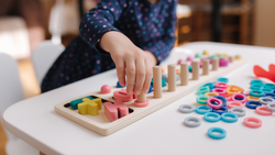 A kids' hands work on a sorting puzzle.