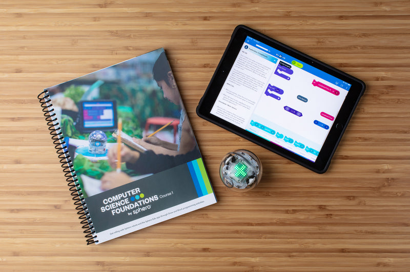 Computer Science Foundations Course 1 book with a Sphero BOLT and tablet on a desk.