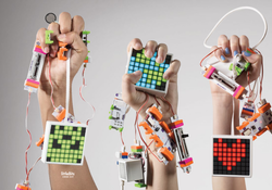 Three hands holding littleBits from the Code Kit.