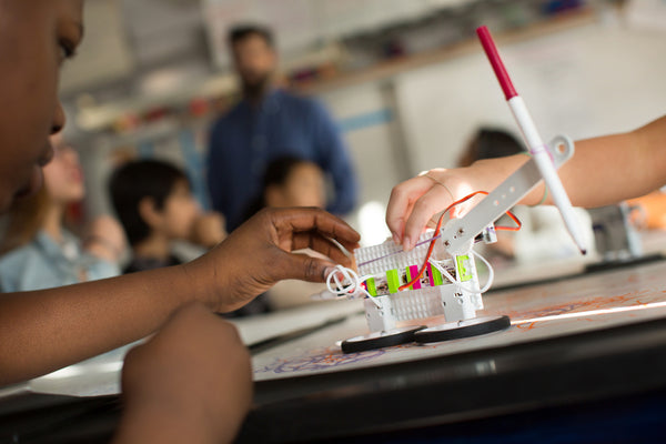 A boy builds a littleBits Doodle Wizard invention in his classroom.