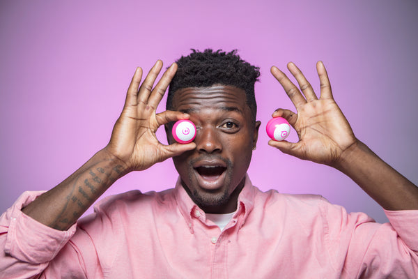 A man holds two pink Sphero Minis in his hands. 