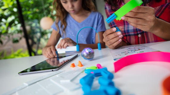 A girl and her mom work on STEAM-based activities with Sphero Mini Activity Kit at a table at home.
