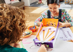 A boy and a girl play an arcade STEM game built out of littleBits and cardboard. STEM activites and games are a great way to bring learning and fun together.