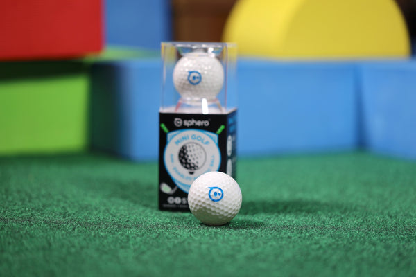 The Sphero Mini Golf in its packaging and out sitting on green turf.