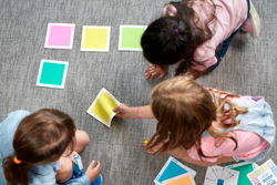 An overhead view of three children using indi's color tiles.