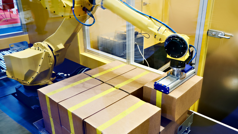 An industrial robot packs boxes in a warehouse.