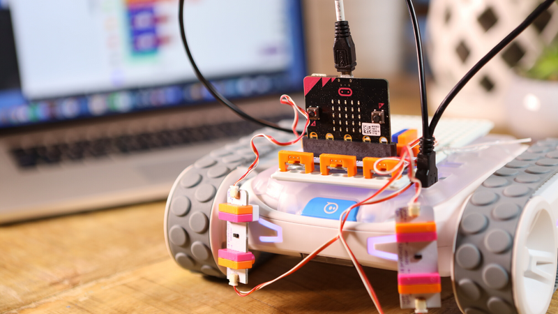 A littleBits microbit adapter invention on top of a Sphero RVR robot on a desk in front of a laptop.