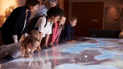 Students and teachers look at a large interactive map.