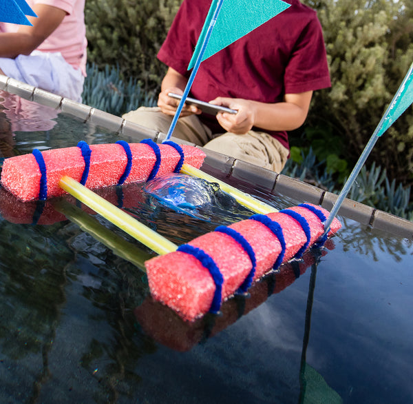 Kids using BOLT waterproof robot to drive boat in water.