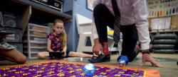 A teacher and students work with Sphero robot learning devices to learn about shapes and numbers.