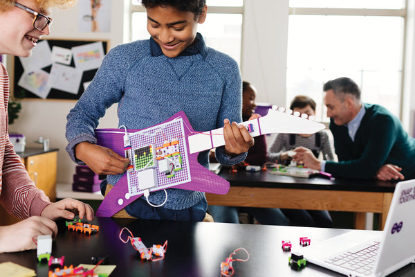 Two boys building a guitar with littleBits circuit STEAM kit.
