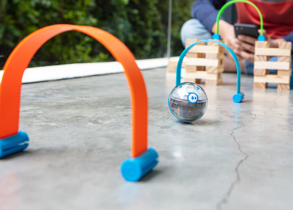 A toy robot ball driving through a blue and orange archway. 