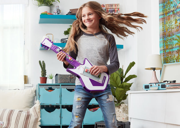 Girl having fun playing with electronic music guitar.