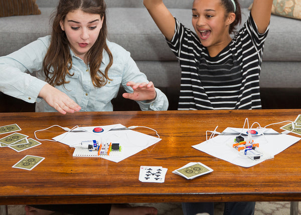 Two girls playing with cards and littleBits invention.