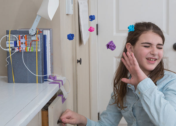Girl being hit with projectiles from littleBits room defender invention.