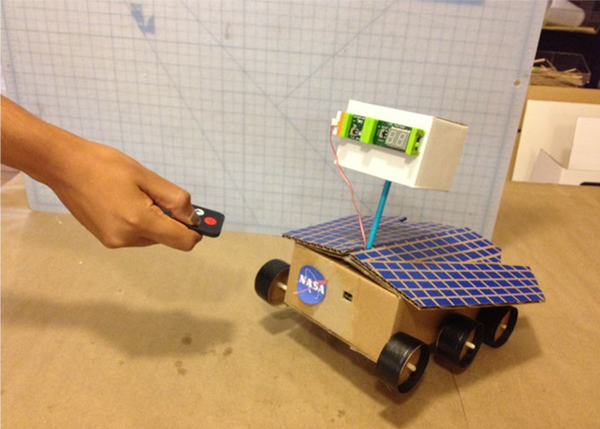 Person pointing a remote at a DIY space rover.