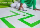 Girl programming mini through a green maze taped on the ground.