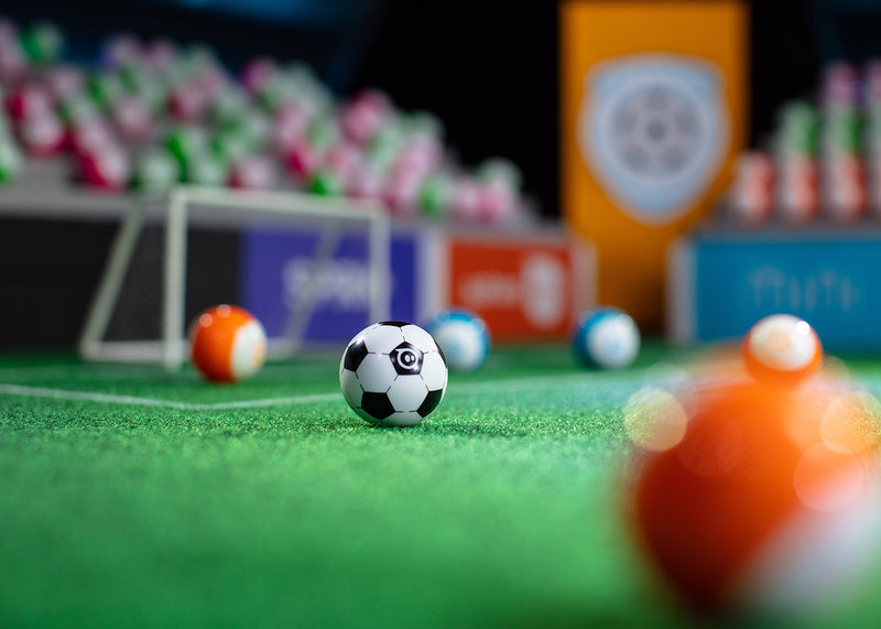 Mini Soccer surrounded by other mini robotic balls on a miniature soccer field.