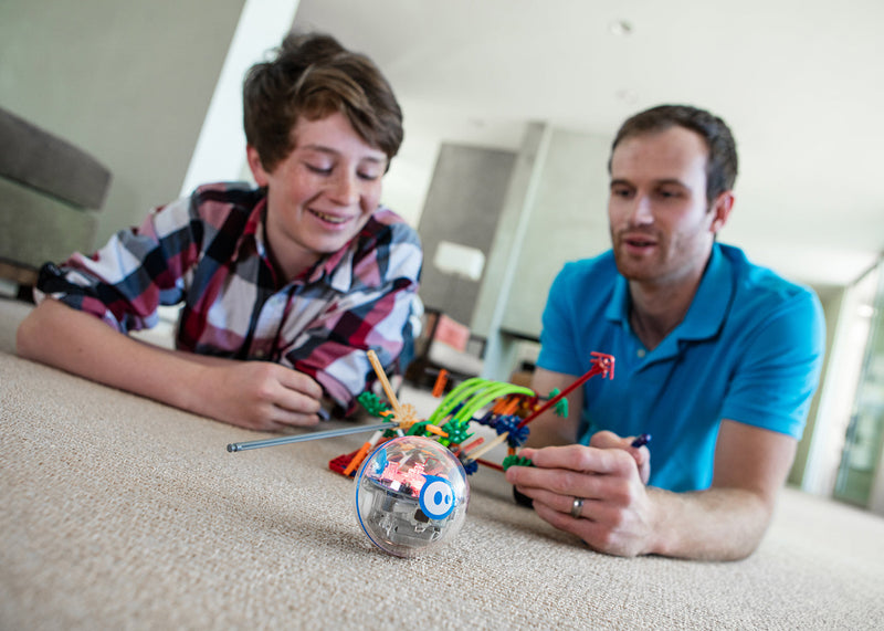 Father and son on living room floor building a chariot with STEM robotic toy.